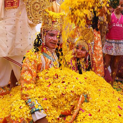 Delhi, India- March 19, 2011: A long forgotten tradition was brought alive at "Delhi Haat" located in New Delhi. The tradition of playing Hoil with flowers. People threw petals of marigold, jasmine and chrysanthemums on each other. In the picture, a pit of  young boy and girl poses as Lord Krishna and Radha.  Flowers are being showered on the duo.